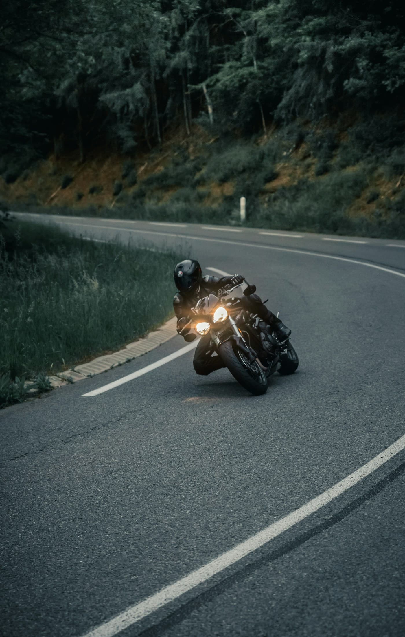 Helmeted motorcyclist riding on a curved roadway